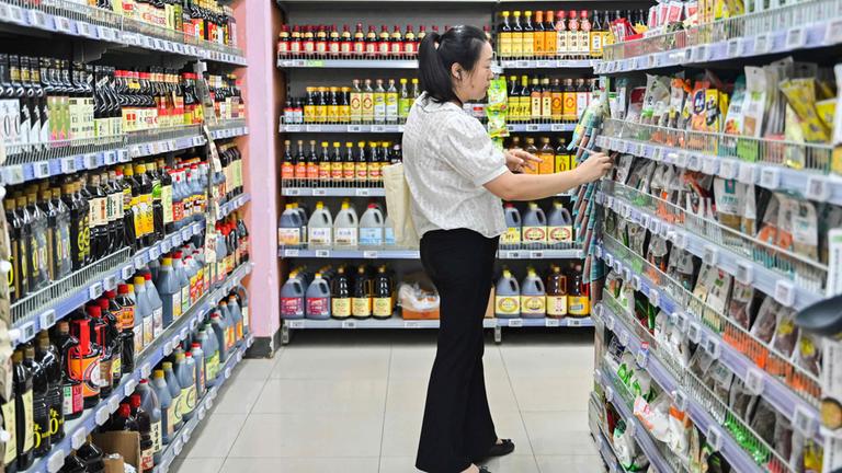 Eine Frau steht vor einem Regal im Supermarkt in Peking.